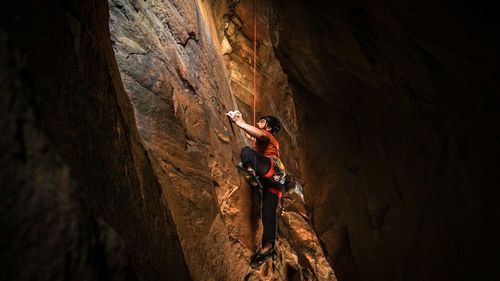 Low angle view of man climbing on rocky mountain