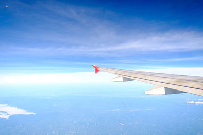 View of airplane wing against cloudy sky