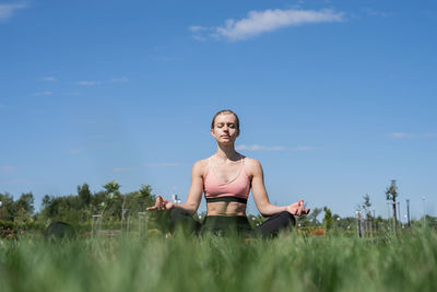  happy woman in sportclothes working out in the park in sunny summer day, meditating
