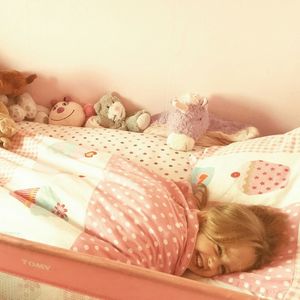 High angle view of cheerful girl lying on bed