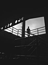 Low angle view of silhouette man standing on staircase