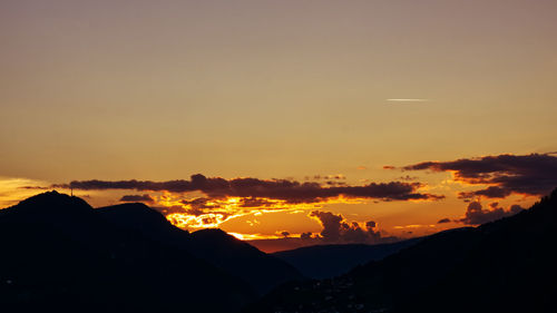 Scenic view of silhouette mountains against orange sky