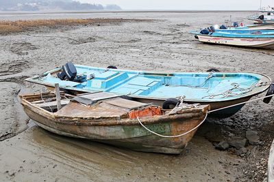 Old boat moored on beach against sky