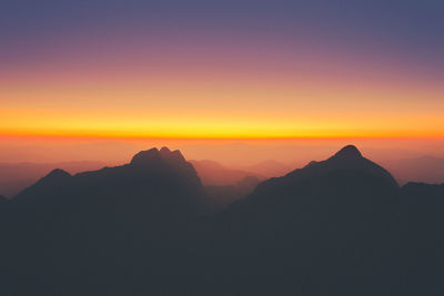 Scenic view of silhouette mountains against orange sky