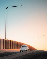 Cars on street against clear sky during sunset