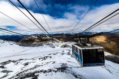 Overhead cable car on snowcapped mountains against sky