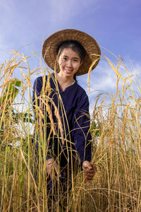 Portrait of young woman in field against sky