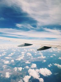 Cropped image of aircraft wing over cloudy sky