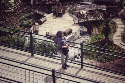 Rear view of woman standing on footbridge