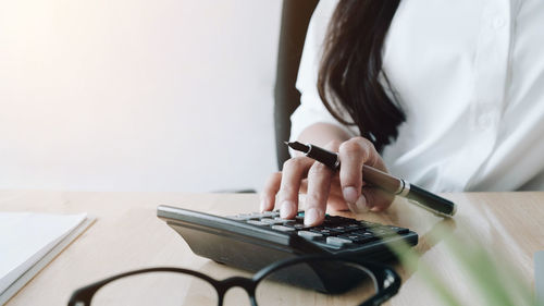 Midsection of woman using mobile phone on table