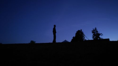 Low angle view of silhouette man standing against clear blue sky