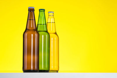 Close-up of empty glass bottle against yellow background