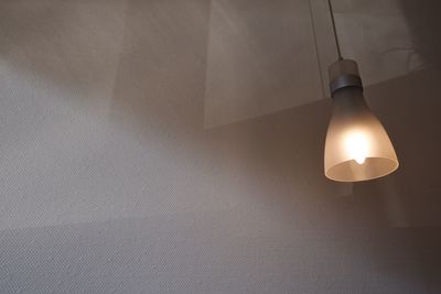 Low angle view of pendant light hanging by wall