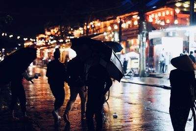 Rear view of people walking in illuminated city at night