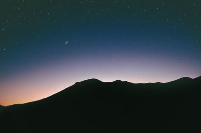 Scenic view of silhouette mountains against clear sky at night