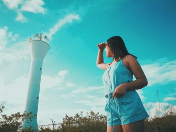 Woman looking at lighthouse against sky