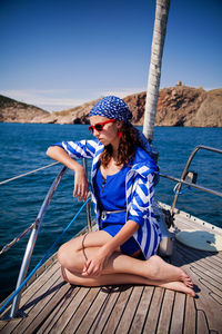 Young woman, nose of the white yacht in a nautical theme. blue jacket, blue scarf and sunglasses