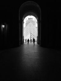 Silhouette of people walking in tunnel