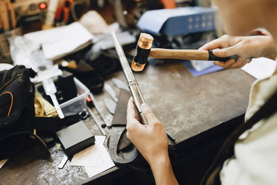 High angle view of female craftsperson resizing jewelry at workshop