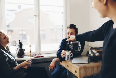 Woman serving coffee to couple in kitchen at home