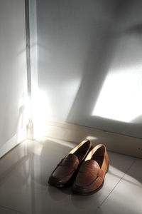 Close-up of shoes on floor against wall at home