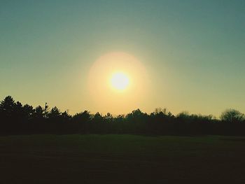 Scenic view of grassy field against sky at sunset