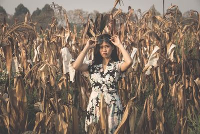 Portrait of woman in sunglasses standing against plants