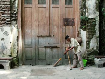 Man sweeping while standing against entrance of building