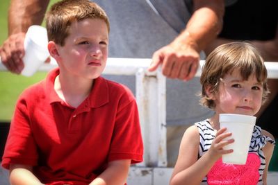 Portrait of sister with brother holding disposable cup