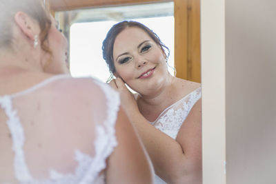 Reflection of smiling woman in mirror at home