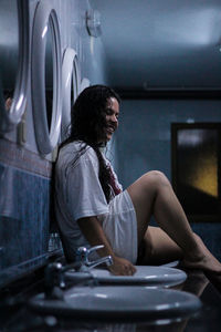 Young woman sitting by sink