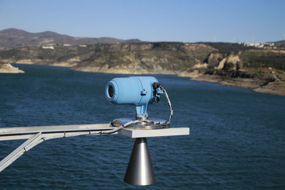 Close-up of coin-operated binoculars by sea against clear sky