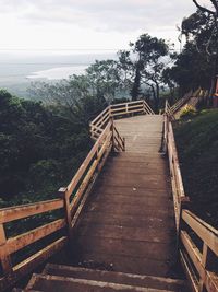 Wooden jetty leading towards sea against sky