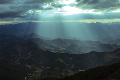 Sunlight streaming through clouds over landscape