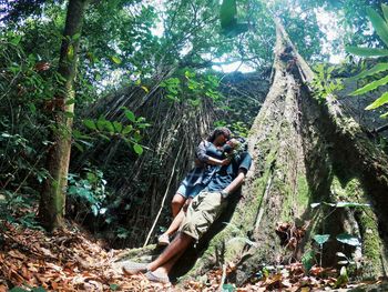 Man climbing on tree trunk in forest