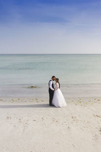 Couple kissing on beach against sky