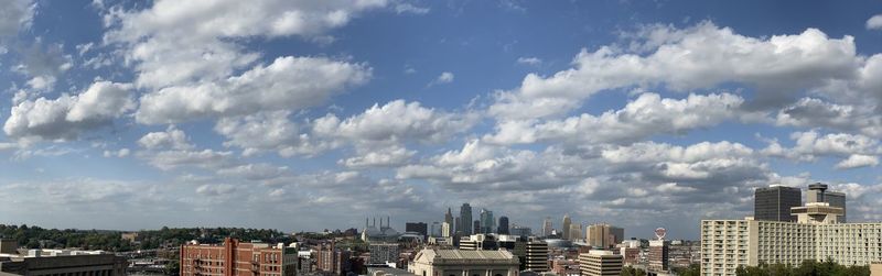 Panoramic view of buildings in city against impressive clouds blue skies. 