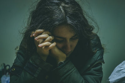 Portrait of woman covering face against wall
