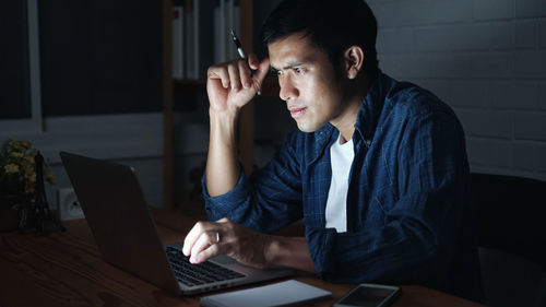 Young man using mobile phone while sitting on table