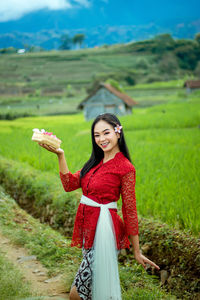 Portrait of an indonesian woman, wearing a red balinese kebaya.