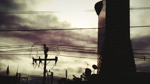 Low angle view of electricity pylon against cloudy sky