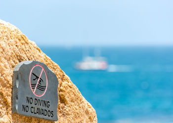 No diving sign on rock by sea