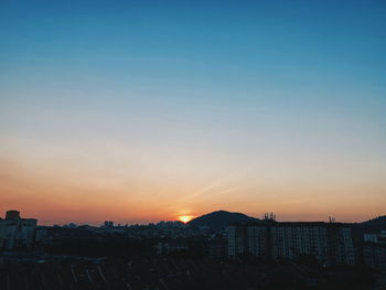 Buildings in city against clear sky during sunset