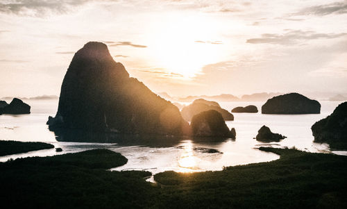 Rocks on beach against sky during sunset