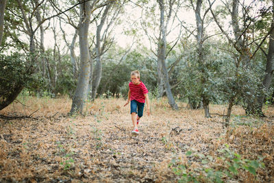 Full length of boy running in forest