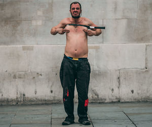 Full length of shirtless man standing against wall