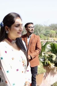 Young couple standing against plants