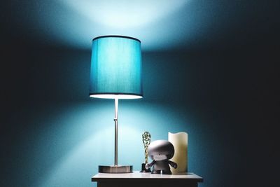 Close-up of electric lamp on table against wall