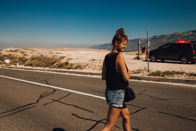 Woman standing on road against sky in city