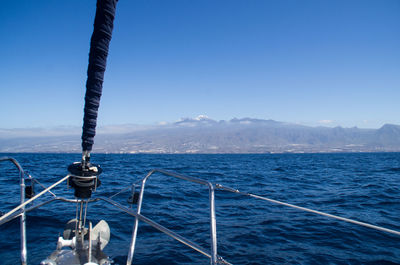 Railing of ship on sea with mountain in background